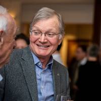 Man holding a drink smiles at another man